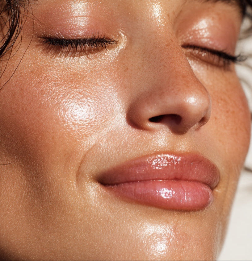 Close-up of a woman's face with a sun-kissed glow, eyes closed.